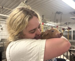 Abigail Dowell smiles while holding pig.