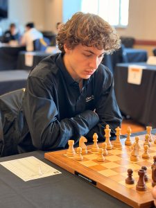 Mahel Boyer sits in front of chess board.