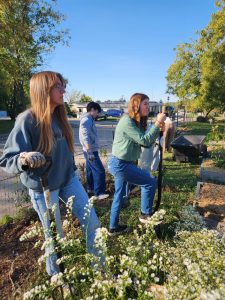 Mayhew stands with foot on shovel among other Sustain Mizzou members in garden.