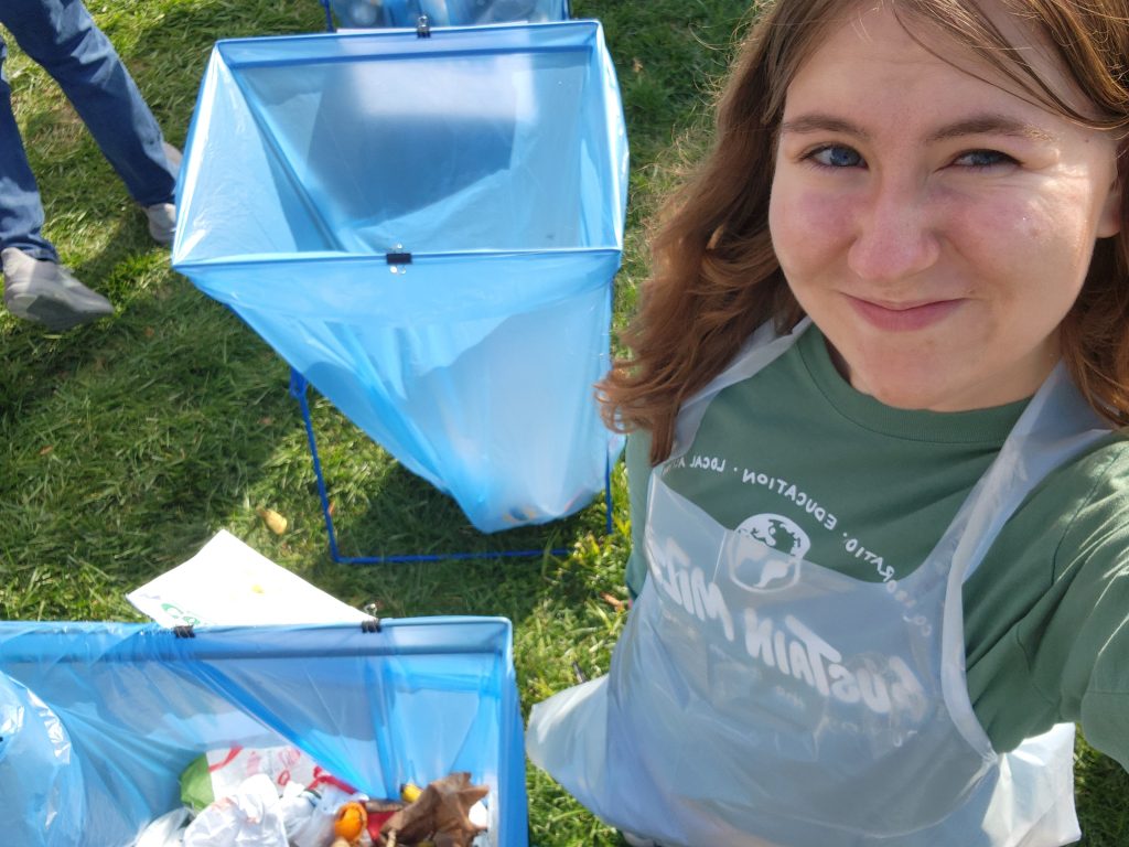 Makayla Mayhew takes selfie with bags full of collected trash.