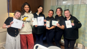 Lauren LaMar stands with other Fight Night fighters and Margot, a pediatric cancer patient at University Hospital. They all hold drawings of eyes.