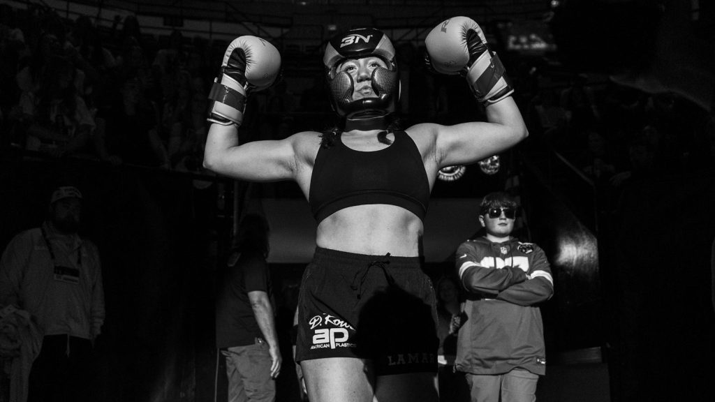 Lauren LaMar walking out of the tunnel at the Hearns Center and holding up her arms in boxing gloves during Mizzou's Fight Night 2026.