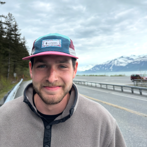 Will Lingle smiling outdoors with a road and mountains behind him.