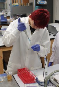 Oscar Bomgaars in lab coat doing research in lab.