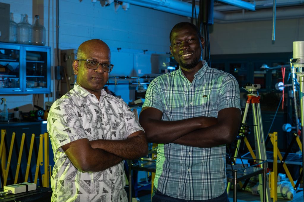 Two researchers stand in front of lab equipment.