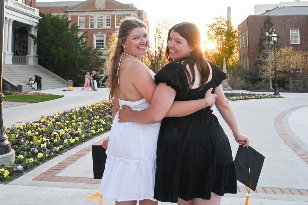 Bell and Beth Foltz smile and look back at the camera while holding their graduation caps on Mizzou's quad.