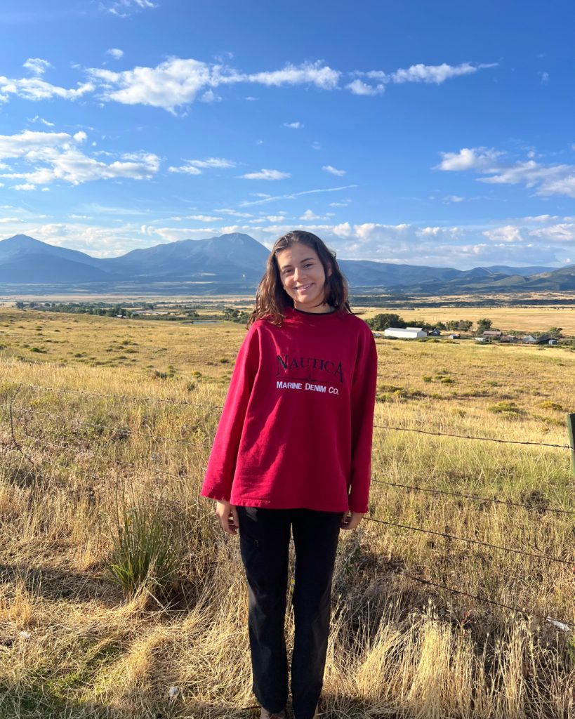 India Williams smiling with a field and mountains behind her.
