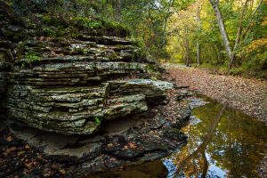 A tiered rock formation along a stream in fall.