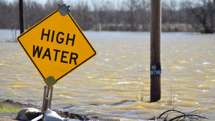 Flood waters from the Mississippi River sweep across a roadway.