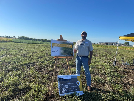 Gurbir Singh in field with posters