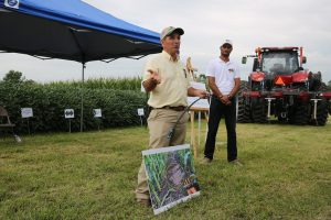 Two men giving a presentation next to a field.