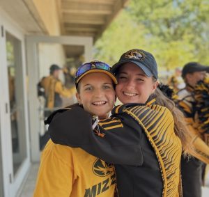Molly Peters in a Marching Mizzou uniform hugging a student.