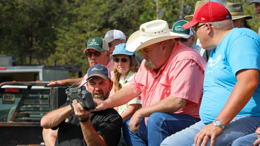 A presenter demonstrates a handheld remote to group of people at Wurdack Field Day.