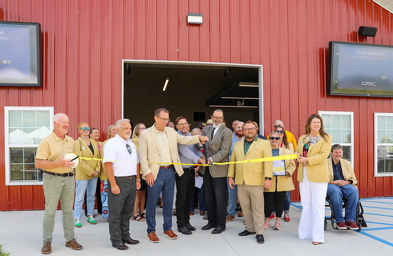 A group cuts a yellow ribbon in front of a new building.