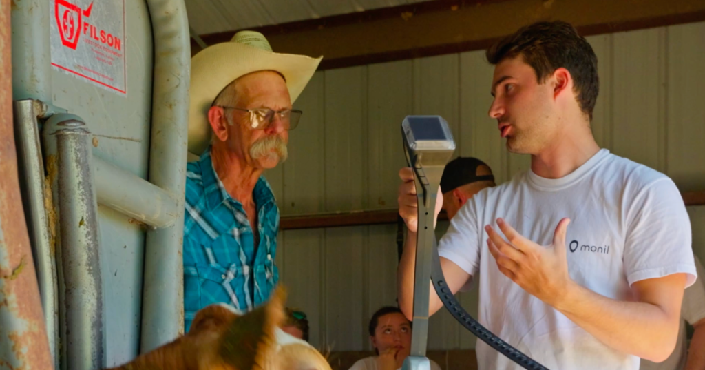 John Miles holds a virtual fencing collar and talks to a cattle producer.