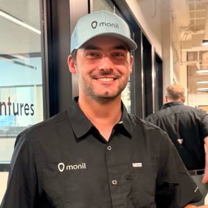 John Miles smiling in a Monil hat and shirt.
