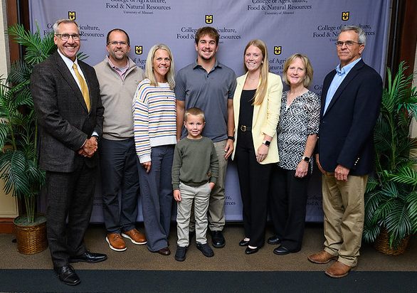 TJ and Andi Belt pose for a picture with their parents, grandparents, younger brother and Dean Daubert.