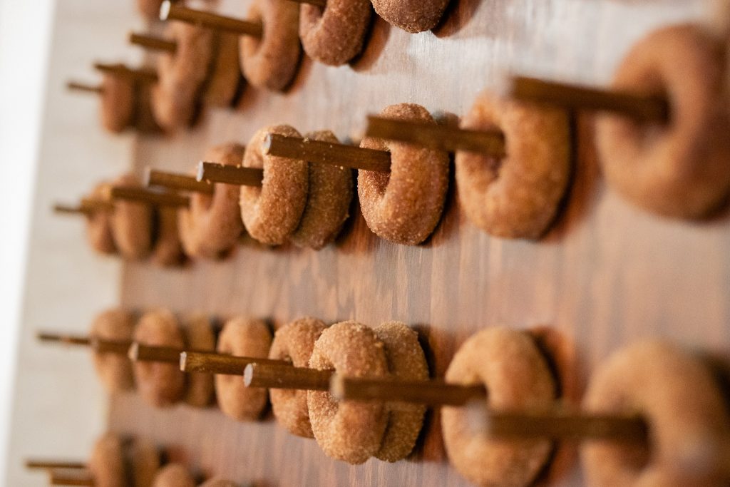 Apple cider doughnuts hang on wooden pegs.