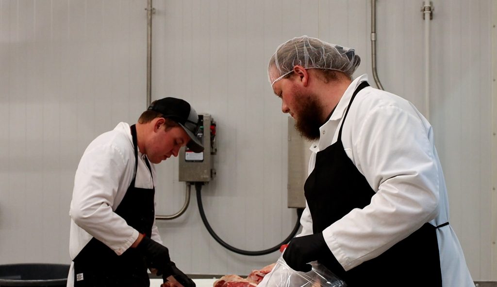 Nick Van Schyndel and a coworker cut and package fresh meat for the Mizzou Meat Market.